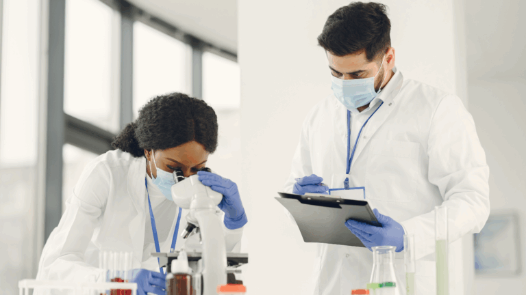Two MedTech professionals wearing lab coats and masks review data and samples in a clinical laboratory. The image reflects the collaborative, high-precision environments Axion supports, where technical, regulatory and diagnostic expertise converge to drive innovation in medical technology.
