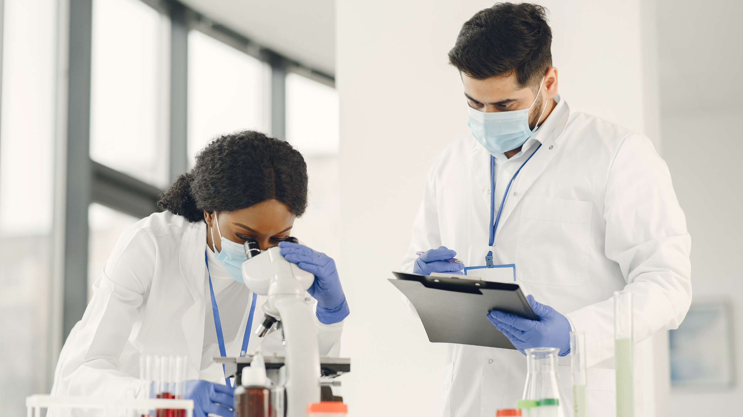 Two MedTech professionals wearing lab coats and masks review data and samples in a clinical laboratory. The image reflects the collaborative, high-precision environments Axion supports, where technical, regulatory and diagnostic expertise converge to drive innovation in medical technology.